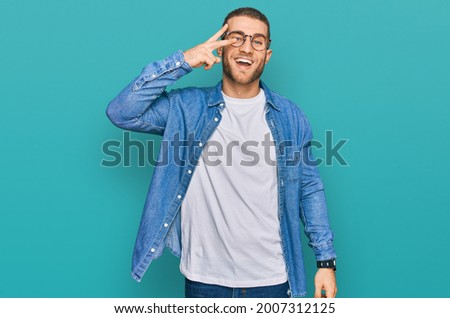 Young caucasian man wearing casual clothes doing peace symbol with fingers over face, smiling cheerful showing victory 
