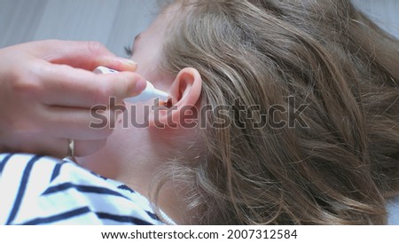 Caucasian Mother Applying Drop of Liquid Antibiotic Steroid Medicine into Ear of Young Child Royalty-Free Stock Photo #2007312584