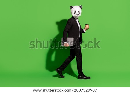 Photo of programmer guy go hold takeout coffee cup netbook wear panda head black tux isolated on green color background