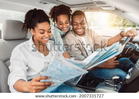 Cheerful African American Family Looking At Road Map Sitting In Car. Parents And Daughter Choosing Destination For Summer Road Trip Together. Local Tourism Concept. Selective Focus Royalty-Free Stock Photo #2007331727