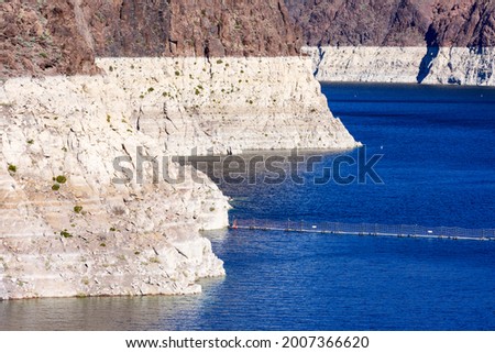 Record low water level of shrinking Lake Mead exposed white surface on rocky banks amid severe drought in American West. The lake is key reservoir along Colorado River Royalty-Free Stock Photo #2007366620
