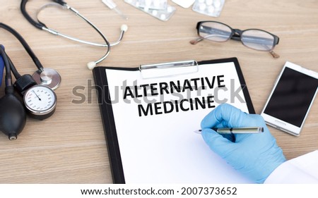 doctor's hand writes the inscription Alternative medicine on white paper on the table