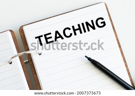 In the notebook text Teaching next to black marker on white background