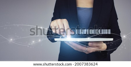 Inventory Logistics Production Concept. White tablet in businesswoman hand with digital hologram Bar Code Price Tag on grey background. Warehouse and logistics concept