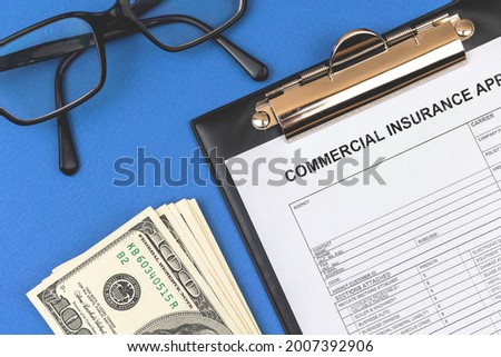 Commercial insurance claim form. Office desk with official contract and agreement of property. Desktop with money and clipboard. Top view 