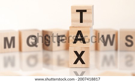 wooden cubes with letters tax arranged in a vertical pyramid, white background, reflection from the surface of the table, business concept