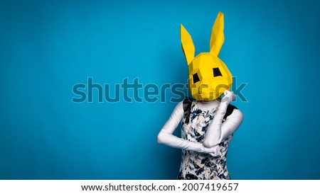 Girl in a dress, yellow hare's head on a girl, blue background