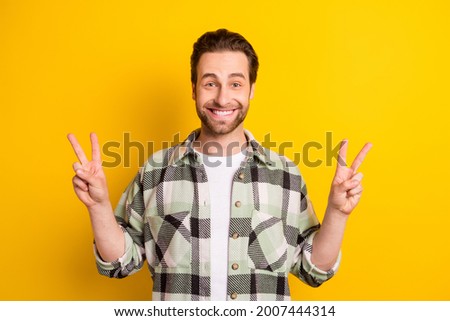 Photo of young cheerful man happy positive smile show peace cool v-sign isolated over yellow color background