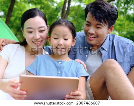 Happy family of three uses tablet computer outdoors high quality photo