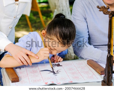 Happy family of three writing calligraphy outdoors high quality photo