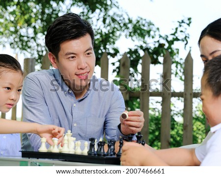 Happy family of four playing chess in the park high quality photo