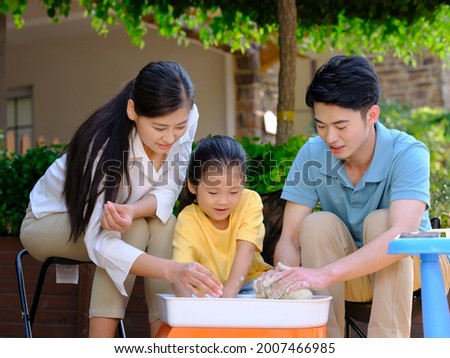Happy family of three doing pottery together outdoors high quality photo