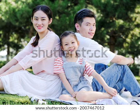 Happy family of three sitting on the park grass high quality photo