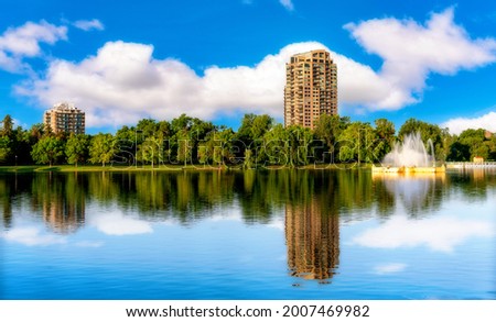 Clouds in the sky beyond an apartment building with reflection in pond