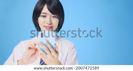 Asian female student using a smart phone. Royalty-Free Stock Photo #2007472589