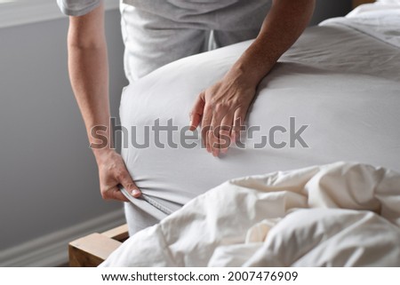 Woman is putting on a fitted sheet on a mattress while making the bed Royalty-Free Stock Photo #2007476909
