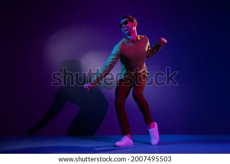 Full length photo of young chill guy dance wear eyewear sweater pants isolated on blue color background