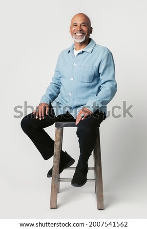 Happy retired man sitting on a stool Royalty-Free Stock Photo #2007541562