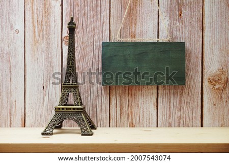 Empty wooden hanging on wooden background with eiffel tower home decor on wooden shelve