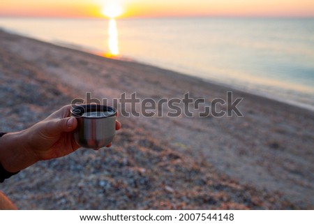 Sunrise at the sea. Beautiful sunrise on the ocean. Meet the dawn early in the morning with a cup of coffee in your hands. Cup of coffee at sunrise on the beach. Summer at the sea. Morning by the sea