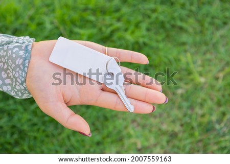 Woman holding a keyring with green grass background.