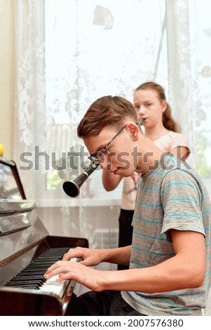 The girl plays the clarinet, and the guy with glasses accompanies her on the piano. Rehearsal and training at a music school.