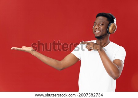 Cheerful man of African appearance in headphones red background Copy Space