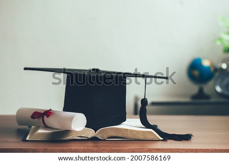 A mortarboard and graduation scroll on open books on the desk.education learning concept Royalty-Free Stock Photo #2007586169