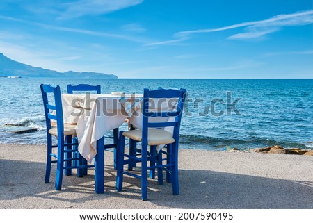 Blue chairs and table in typical Greek tavern near the sea in Kissamos town. Crete, Greece Royalty-Free Stock Photo #2007590495