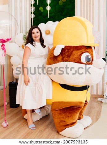 A woman stands next to a growth doll for a children's holiday. entertainment and animation for children at a birthday party or prom in kindergarten and elementary school.