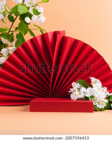 Red podium paper oriental fan flowering branch with buds pink pastel background