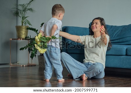 Happy mother day. child son congratulates mother on holiday and gives flowers. congratulating her on mother's day during holiday celebration at home