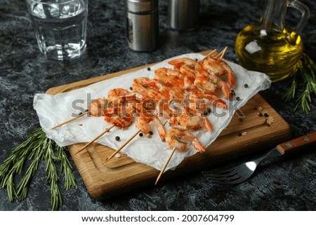 Board with grilled shrimps on black smokey table