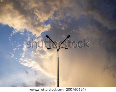 Bottom view of a tall lamppost with four lamps. Beautiful blue, golden and brown evening sky.
