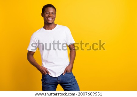Photo of cheerful young dark skin happy man hold hands jeans pockets isolated on shine yellow color background