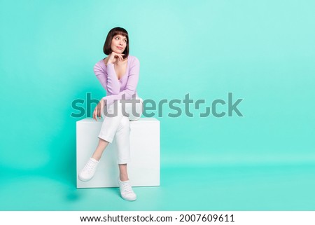 Full length body size photo woman sitting wearing fashionable clothes looking blank space isolated bright teal color background