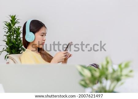 Asian woman happy cute beautiful using phone for listening to music with earphones.