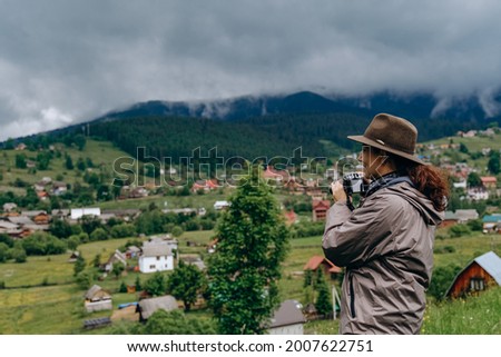 Woman photographer travels in the mountains in summer. Hiking in Europe. A woman photographs alpine landscapes.