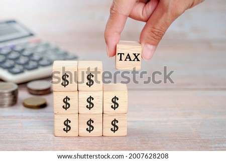 Wooden cubes with the word Tax and $ , on a wooden table.