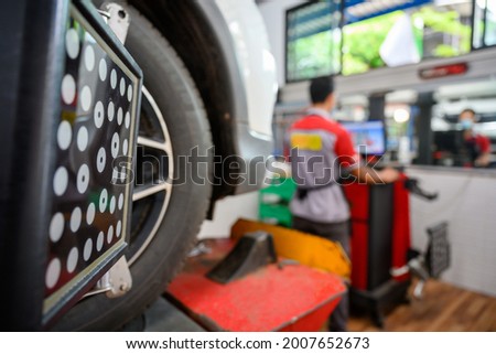 Auto service mechanic installing wheel alignment sensor on tire during vehicle suspension alignment adjustment. and set the car wheel center at the auto repair station Royalty-Free Stock Photo #2007652673