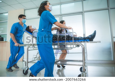 a group of medics or doctors carrying male patient on hospital gurney to emergency or operation room, urgent caseon  gurney being pushed at speed through a hospital. Royalty-Free Stock Photo #2007663266
