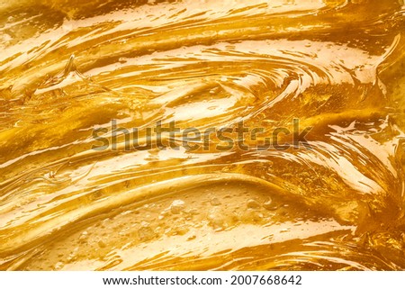 Transparent smear and texture of golden cosmetic gel on a white background.