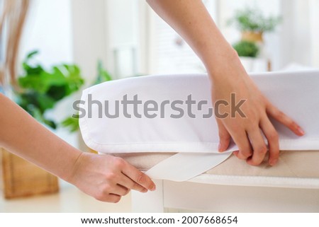 Women's hands are pulling a waterproof mattress topper with an elastic band on the mattress. Leakage protection. The focus on the photo is directed to the bottom of the frame, the other hand is blurry Royalty-Free Stock Photo #2007668654