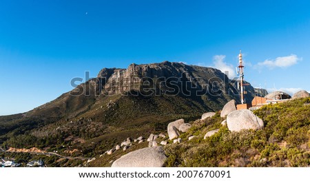 A cell tower in a hill with a mountain in the background. 