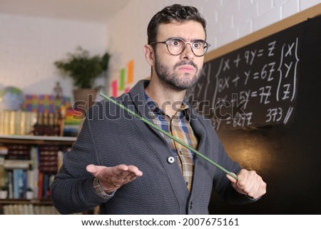 Old fashioned angry teacher holding stick in classroom Royalty-Free Stock Photo #2007675161