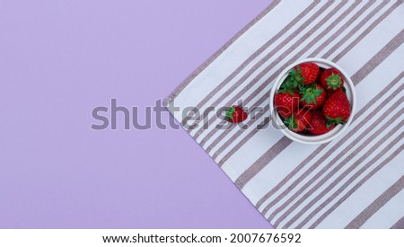 A top view of a bowl with strawberries on a kitchen towel. Raw summer food concept.