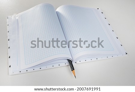 Expanded checkered notebook with open sheets and pencil. Selective focus. Blurred background.
