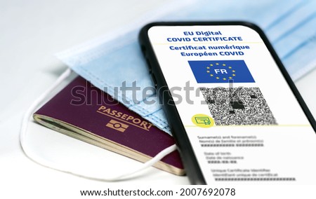 French EU Digital COVID Certificate with the QR code. Translation from french "European COVID digital certificate". Mobile phone over a surgical mask and a french passport. Health passport Royalty-Free Stock Photo #2007692078