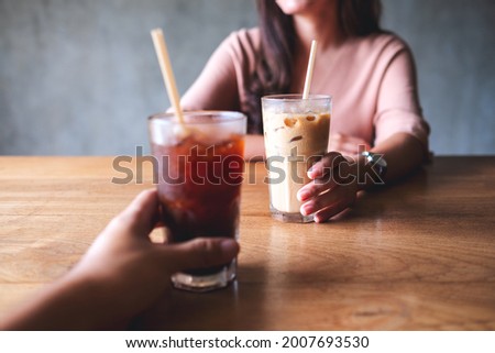 Closeup image of a couple people holding and drinking coffee together in cafe