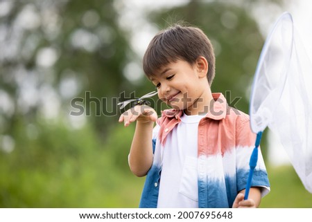 boy with dragonfly on holding hand in the nature background 